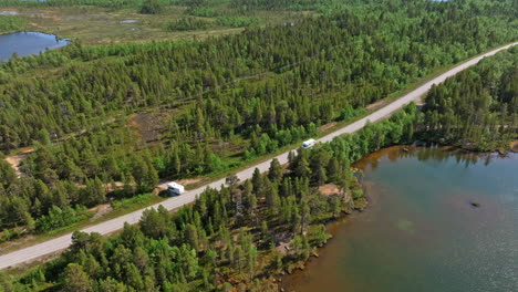 AERIAL:-Camper-van-passing-a-parked-RV-on-a-road-in-the-arctic-wetlands,-sunny-day