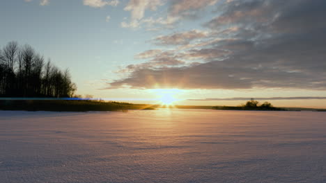 Dolly-right-over-snow-covered-winter-lake-in-sunset,-Sweden