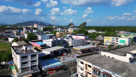 Beautiful-aerial-view-flight-of-krabi-town-in-southern-thailand,-showing-a-mix-of-buildings,-a-river,-the-sea,-and-forested-hills-in-the-background