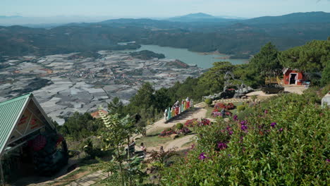 Un-Grupo-De-Turistas-Disfruta-De-Majestuosos-Paisajes-Impresionantes-En-El-Parque-Lang-Biang-Mountain-View-Point-En-Los-Invernaderos-Industriales-Del-Campo-De-Da-Lat,-Tierras-De-Cultivo-Junto-Al-Lago-Suoi-Vang-Y-Cordilleras-Cubiertas-De-Bosques.