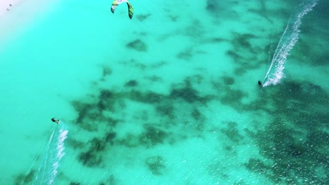 Kite-surfer-gliding-over-vibrant-turquoise-waters-near-a-pristine-white-sand-beach