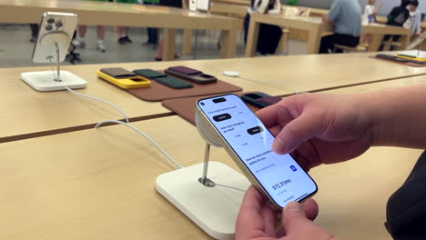 Bewegung-Eines-Mannes,-Der-Im-Apple-Store-Mit-Einem-IPhone-15-In-4K-Auflösung-Spielt