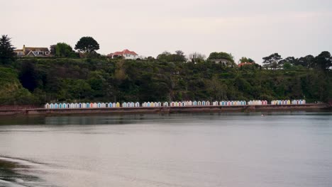 Una-Hilera-De-Cabañas-De-Playa-Tradicionales-Inglesas-Con-Puertas-Pintadas-De-Colores-En-El-Destino-Costero-De-Babbacombe,-Devon,-Inglaterra