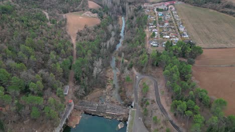 San-ponce-reservoir-with-surrounding-forest-and-nearby-village,-barcelona,-aerial-view