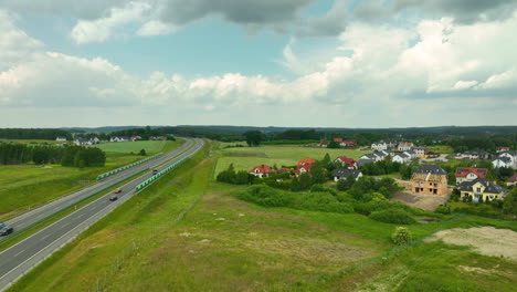 Vista-Aérea-De-Una-Carretera-Que-Atraviesa-Un-Paisaje-Rural-Con-Casas-Residenciales-Cercanas