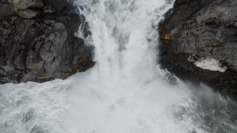 Poderosa-Cascada-De-Agua-Que-Fluye-Desde-Rocas-Volcánicas-De-Basalto-En-Islandia