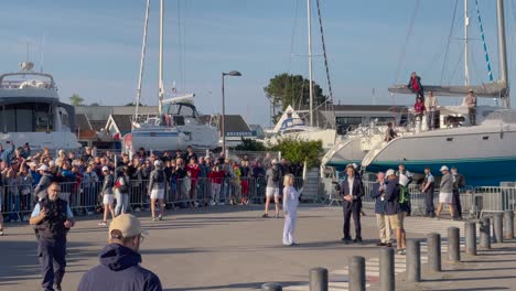 Blonde-lady-holding-and-showing-the-Paris-2024-Olympic-torch-flaming-on-a-sunny-day-in-France-surrounded-by-bodyguards-and-a-street-crowd