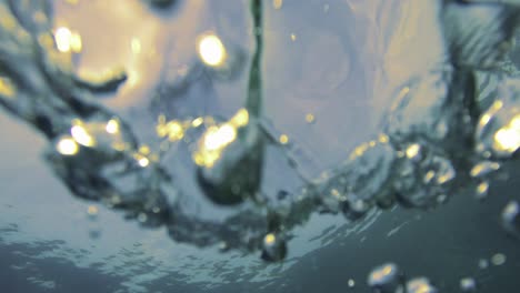 A-woman-snorkeler-floats-in-the-water,-silhouetted-against-the-sunset-sky,-while-bubbles-rise-from-below