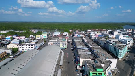 Nice-aerial-view-flight-of-krabi-town-in-southern-thailand,-showing-a-mix-of-buildings,-a-river,-the-sea,-and-forested-hills-in-the-background