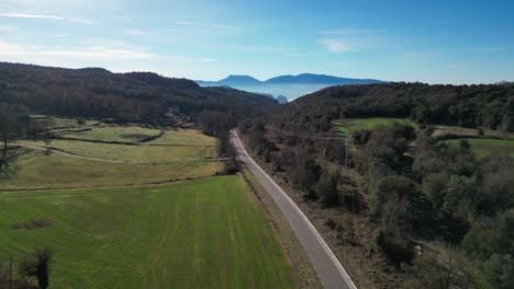 Eine-Malerische-Straße-Schlängelt-Sich-Durch-üppige-Grüne-Felder-Und-Bewaldete-Hügel-Unter-Einem-Klaren-Blauen-Himmel