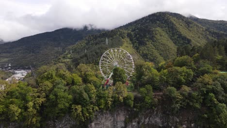 Aerial-view-of-Ferris-Wheel-on-top-of-mountains-surrounded-by-forest-cloud-fog-valley-city