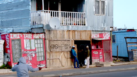 Two-Africans-chat-outside-township-makeshift-informal-SPAZA-shop-in-Zwelihle