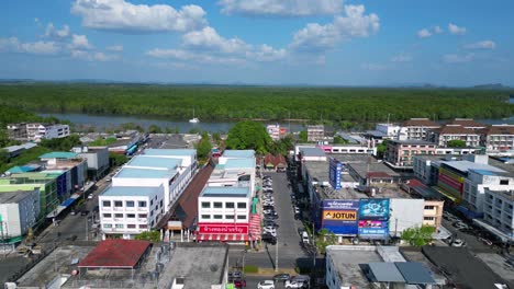 Smooth-aerial-view-flight-of-krabi-town-in-southern-thailand,-showing-a-mix-of-buildings,-a-river,-the-sea,-and-forested-hills-in-the-background