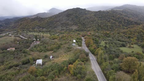 Aerial-view-of-mountains-village-country-road-in-beautiful-green-meadows-mountains