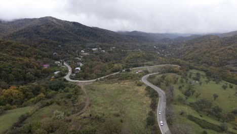 Aerial-view-of-mountains-village-country-road-in-beautiful-green-meadows-mountains-valley