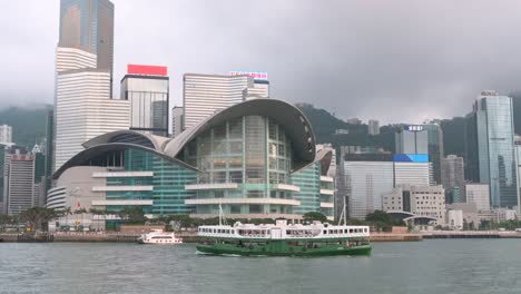 A-Star-Ferry-sails-across-Victoria-Harbour,-with-the-Hong-Kong-Convention-and-Exhibition-Centre-and-the-skyscrapers-of-Hong-Kong-Island's-financial-district-forming-the-backdrop