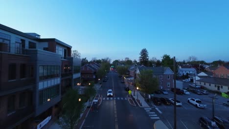 FPV-approaching-flight-along-street-of-American-town-with-Wilbur-Chocolate-Factory-at-dusk