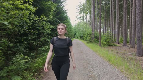 Explora-La-Serena-Belleza-De-La-Naturaleza-Mientras-Una-Alegre-Joven-Se-Embarca-En-Un-Tranquilo-Viaje-A-Través-De-Un-Exuberante-Sendero-Forestal,-Deleitándose-Con-Las-Maravillas-Del-Viaje-Y-La-Aventura.