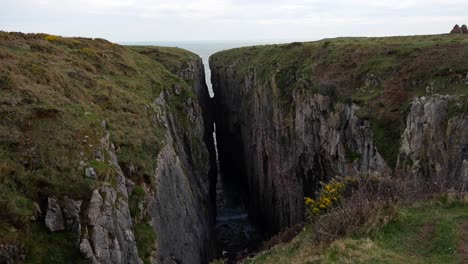 Agua-Del-Océano-Entrando-En-El-Salto-Del-Cazador-A-Través-De-La-Roca-Caliza,-Gales