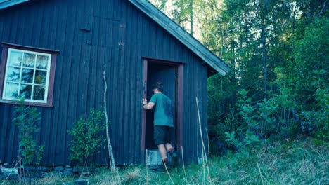 Un-Hombre-Entrando-En-Un-Refugio-De-Madera-En-Medio-De-Una-Montaña-Forestal