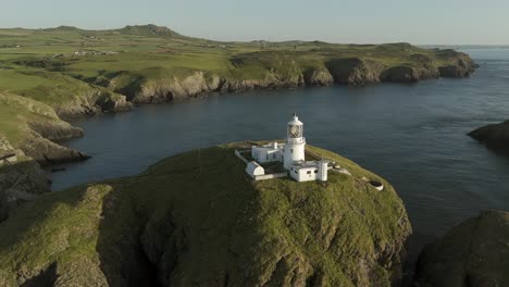 An-aerial-view-of-the-of-Strumble-Head-lighthouse-in-Pembrokeshire,-South-Wales,-on-a-sunny-summer-evening