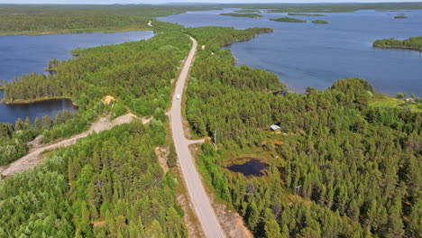 Panoramic-drone-shot-following-a-RV-driving-on-a-polar-road,-summer-in-Lapland