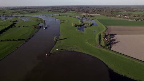 Pan-showing-waterway-intersection-of-Twentekanaal-and-river-IJssel-with-shadow-of-moving-blades-of-wind-turbine