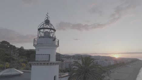 Low-to-high-video-of-the-Calella-lighthouse-on-a-beautiful-sunrise,-located-in-Calella,-Catalunya,-Spain,-shot-in-Dlog