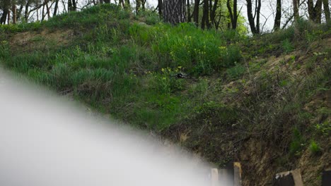 Rack-focus-over-male-shoulder-of-drone-hover-near-green-grass-hill,-Czechia