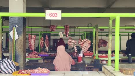 A-senior-female-trader-is-waiting-for-a-stall-selling-meat