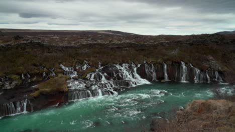 Hraunfossar-Waterfalls-with-flowing-river-in-Icelandic-landscape-during-cloudy-day