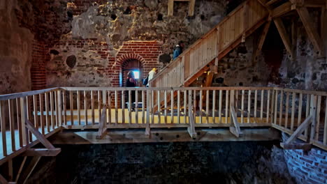 Visitors-explore-the-wooden-staircases-and-brick-walls-inside-historic-Bauska-Castle