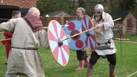 Medieval-reenactors-fighting-with-shields-and-spears-in-a-simulated-battle,-their-expressions-and-movements-reflecting-intense-engagement-in-the-fight