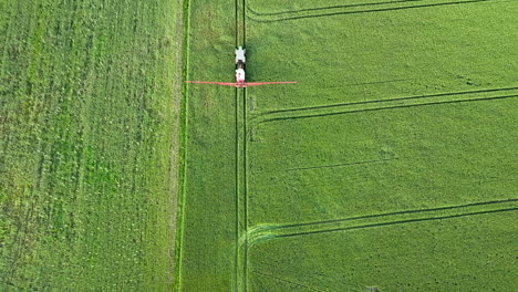 Vista-Aérea-De-Arriba-Hacia-Abajo-De-Un-Tractor-Rociando-Un-Campo-Verde