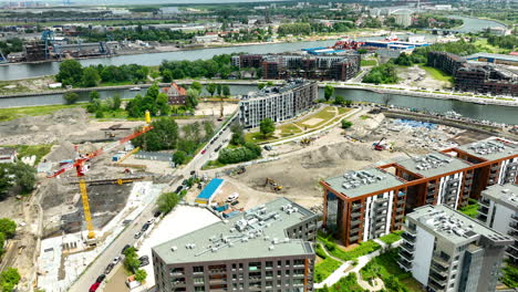 Aerial-of-a-construction-site-in-Gdańsk,-Poland,-featuring-modern-buildings,-cranes,-and-ongoing-construction-activities