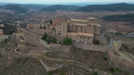 Cardona-castle-overlooking-the-town-and-surrounding-landscape-at-dusk,-aerial-view