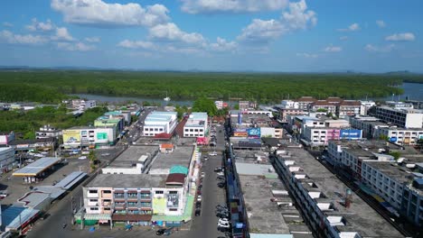 Unbelievable-aerial-view-flight-of-krabi-town-in-southern-thailand,-showing-a-mix-of-buildings,-a-river,-the-sea,-and-forested-hills-in-the-background