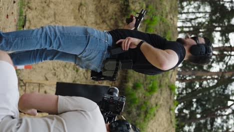 Vertical-shot-of-armed-male-reload-firearm-with-cameraman-behind,-Czechia