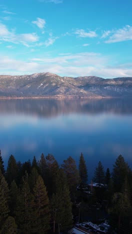 Vertical-Aerial-View,-Lake-Tahoe-USA-on-Sunny-Winter-Day,-Calm-Water-and-Coastal-Forest