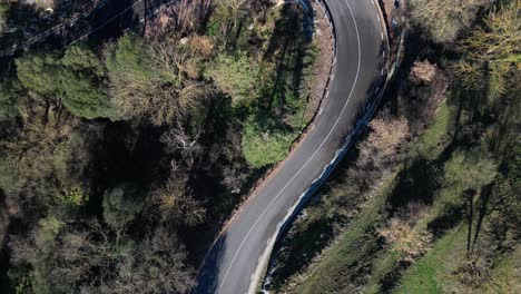 Un-Coche-Circulando-Por-Una-Carretera-Sinuosa-A-Través-De-Un-Bosque-En-La-Comarca-De-Tavertet,-Vista-Aérea