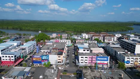 Espectacular-Vuelo-Aéreo-De-La-Ciudad-De-Krabi-En-El-Sur-De-Tailandia,-Que-Muestra-Una-Mezcla-De-Edificios,-Un-Río,-El-Mar-Y-Colinas-Boscosas-Al-Fondo