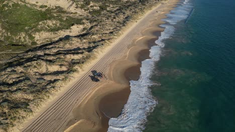 High-aerial-view-over-the-waves-rolling-onto-Preston's-white-sandy-beach