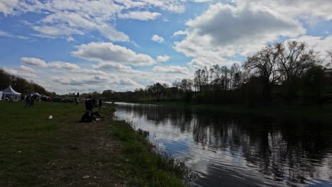 Menschen-Genießen-Das-Bauska-Fischfest-Am-Fluss-Unter-Einem-Teilweise-Bewölkten-Himmel