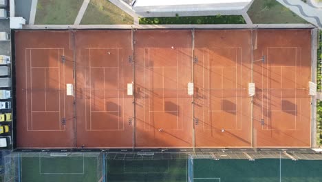 Cinco-Hermosas-Canchas-De-Tenis-De-Tierra-Batida-Al-Amanecer-Filmadas-Con-Drones,-Cámara-Bajada-90-Grados-Y-Luz-Suave