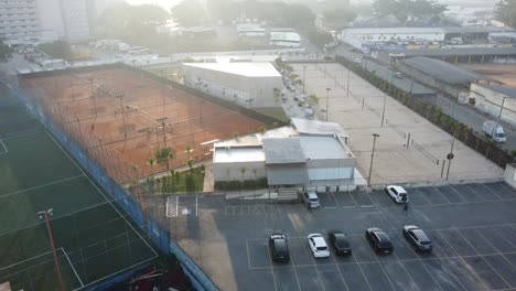 Hermosas-Canchas-De-Tenis-De-Tierra-Batida-Y-Canchas-De-Tenis-De-Playa-Al-Amanecer-Filmadas-Con-Drones,-Movimiento-Hacia-Atrás