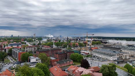 Drone-shot-of-an-urban-construction-site-of-skyline-buildings-on-the-Baltic-Sea-coast-under-cloudy-sky