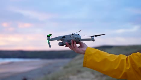 Lanzando-Un-Dron-Desde-La-Mano-Junto-A-La-Costa-Al-Atardecer