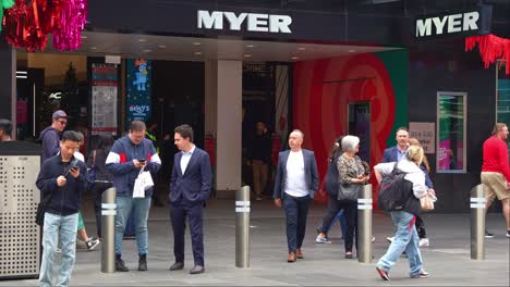 Slow-motion-shot-capturing-Myer's-flagship-store-on-Melbourne's-Bourke-Street-Mall-with-pedestrians-strolling-by,-showcasing-the-bustling-shopping-hub