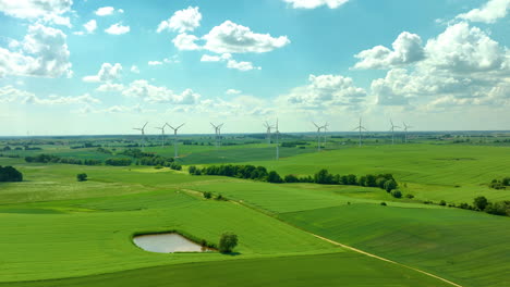 Aerial-view-of-a-wind-farm-in-a-rural-area-with-wind-turbines-scattered-across-green-fields-under-a-bright-blue-sky-with-fluffy-clouds