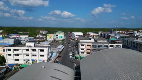 Dramatic-aerial-view-flight-of-krabi-town-in-southern-thailand,-showing-a-mix-of-buildings,-a-river,-the-sea,-and-forested-hills-in-the-background